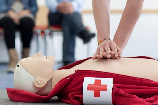 Foto: Eine DRK-Ausbilderin führt den Teilnehmern die Herzdruckmassage an einem Dummy vor.